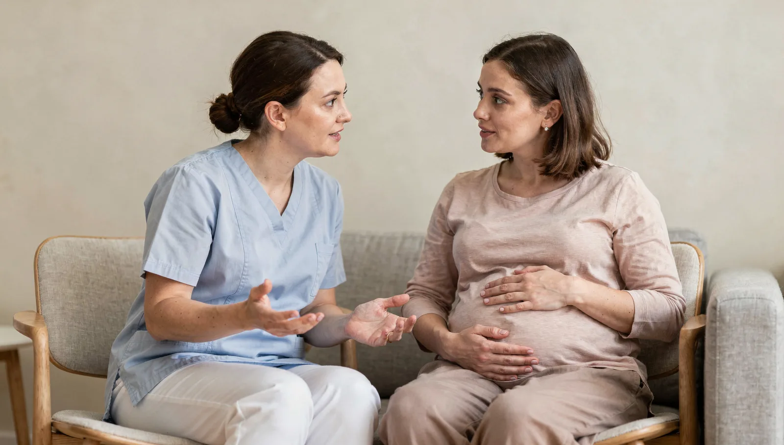 A midwife and a pregnant patient sitting together in conversation, close on the two of them